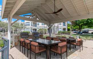 a covered patio with tables and chairs and a grill