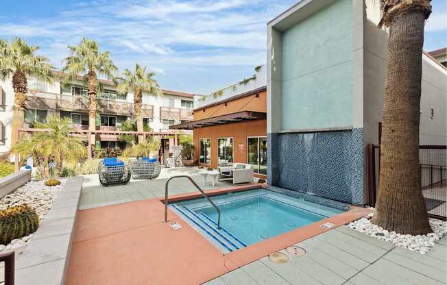A pool surrounded by palm trees and a building.