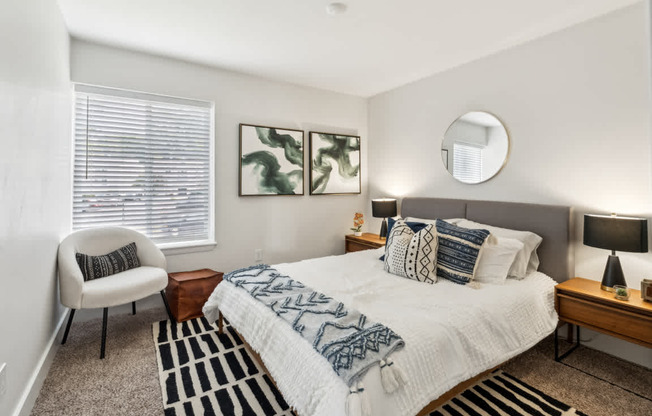 A bedroom with a bed, chair, and two paintings on the wall.