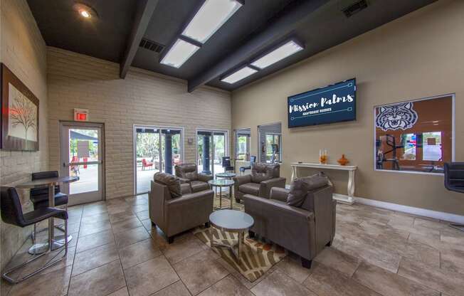 a lobby with couches and chairs and a tv on the wall