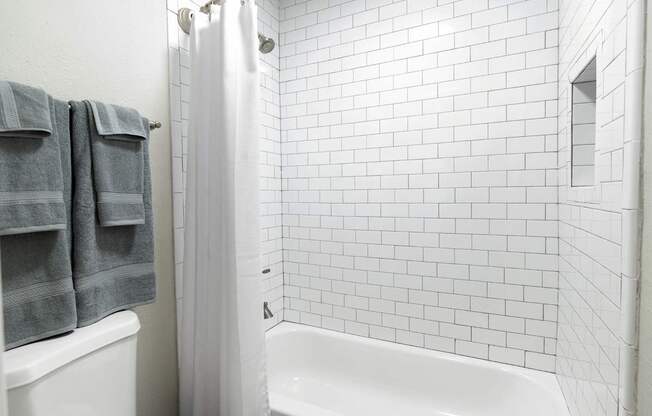 A white tiled bathroom with a white tub at Dunwoody Glen, Atlanta Georgia