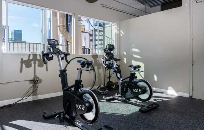 three exercise bikes in a room next to a window