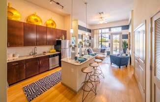 a living room with a kitchen and a bar with stools