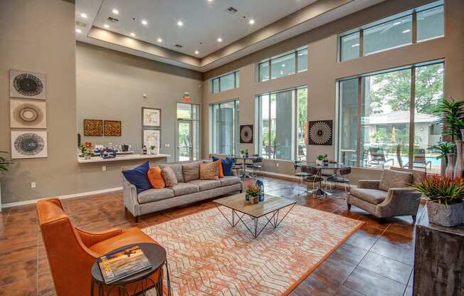 A living room with a grey couch, orange chairs, and a patterned rug.