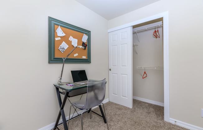 a small desk with a laptop and a lamp in the corner of a room with a closet