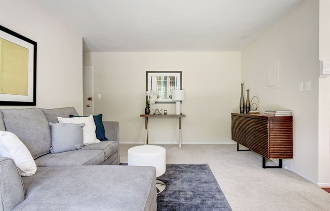 A living room with a grey couch and a white ottoman.
