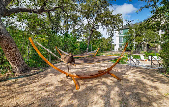 A hammock is suspended between two trees in a park.
