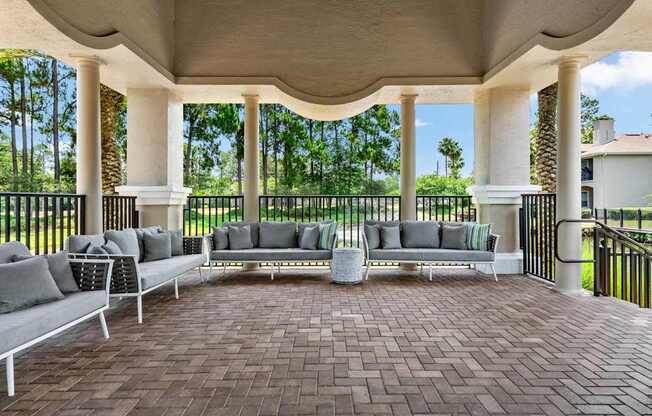 A patio with a white couch and a table with a vase on it.