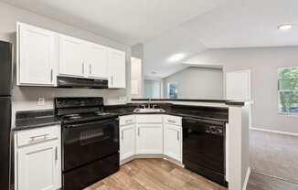 an empty kitchen with white cabinets and black appliances