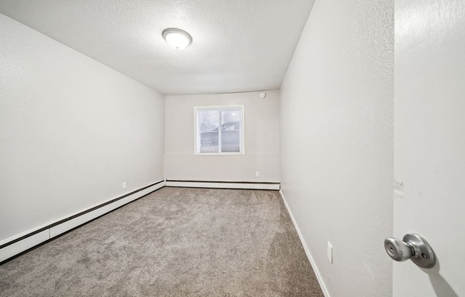 A room with a carpeted floor and a window.