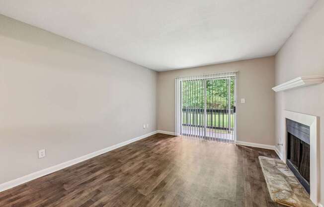 A living room with a fireplace and a sliding glass door leading to a balcony at Gwinnett Square Apartments in Duluth, GA