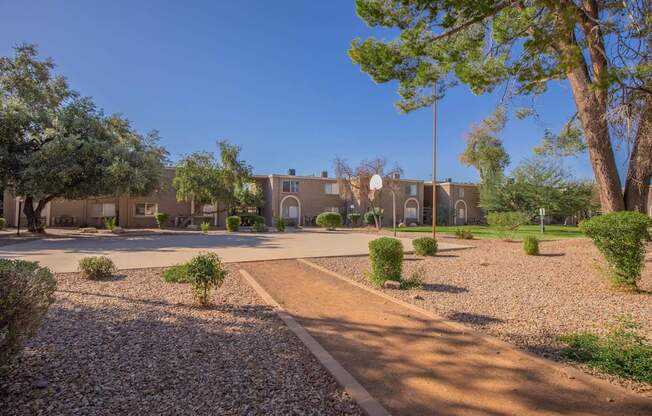A courtyard with a building in the background and a gravel path leading to a door.