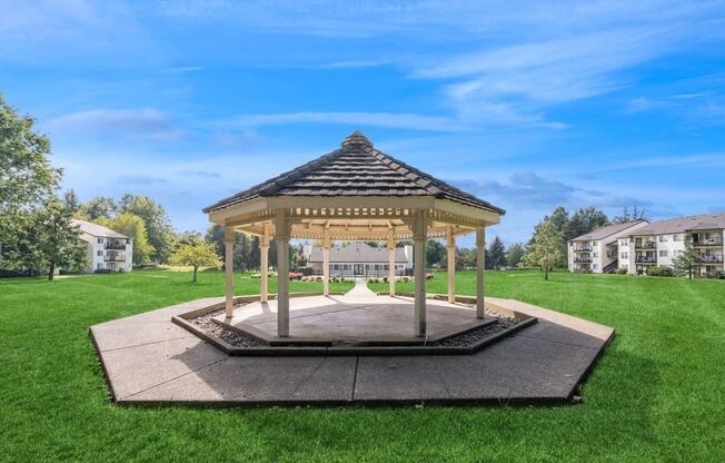 a gazebo in the middle of a yard with houses in the background