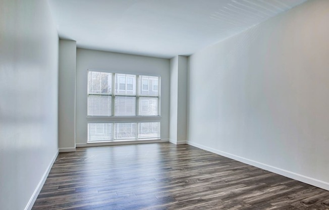 a bedroom with hardwood flooring and a large window