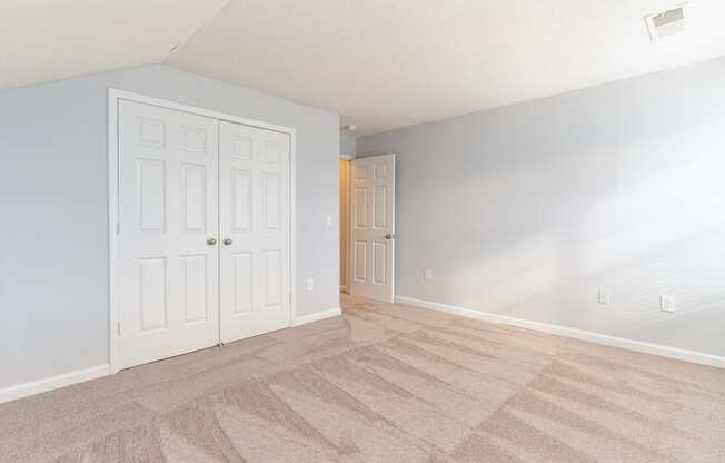 an empty living room with white doors and a carpeted floor