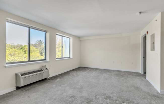 an empty living room with three windows and a radiator on the floor