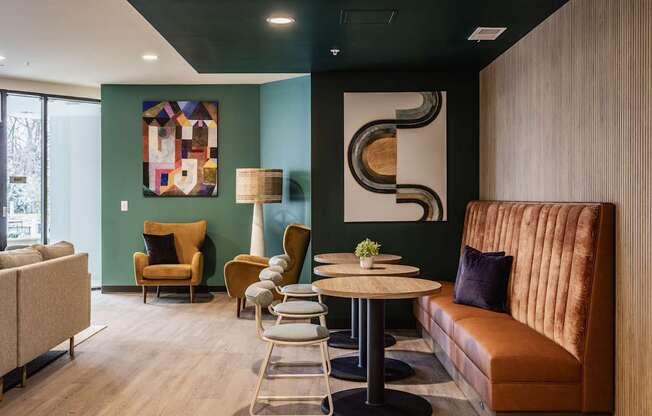 A modern living room with a brown sofa, a round table, and a large abstract painting on the wall.