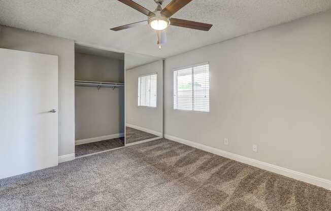 an empty living room with a ceiling fan and a closet