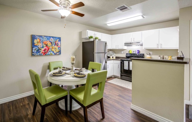 a dining room table and chairs with a kitchen in the background