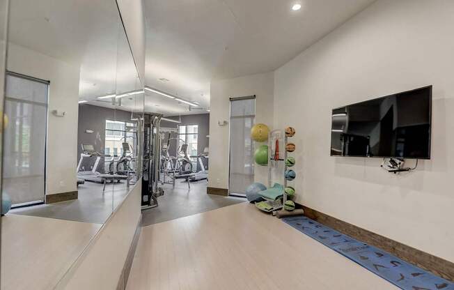 A spacious gym with a mirror on the wall and various exercise equipment at Infinity on the Point Apartments, Dallas, Texas