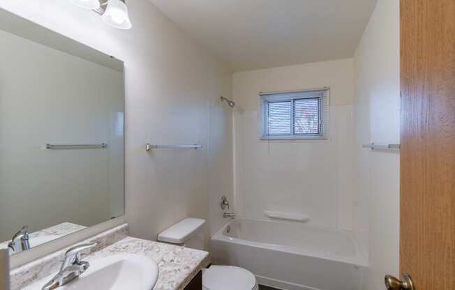 a bathroom with a sink toilet and bath tub and a mirror. Fargo, ND North Manor Apartments