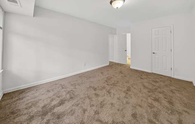 A room with a carpeted floor and two doors.