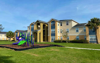 Building Exterior surrounded by shrubs and palm trees with playground view