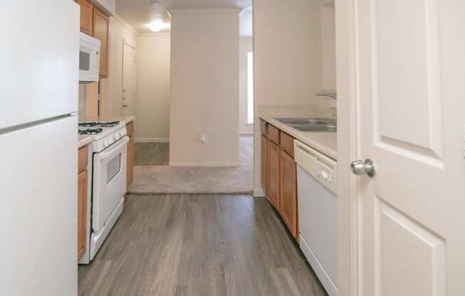 an empty kitchen with white appliances and wood floors