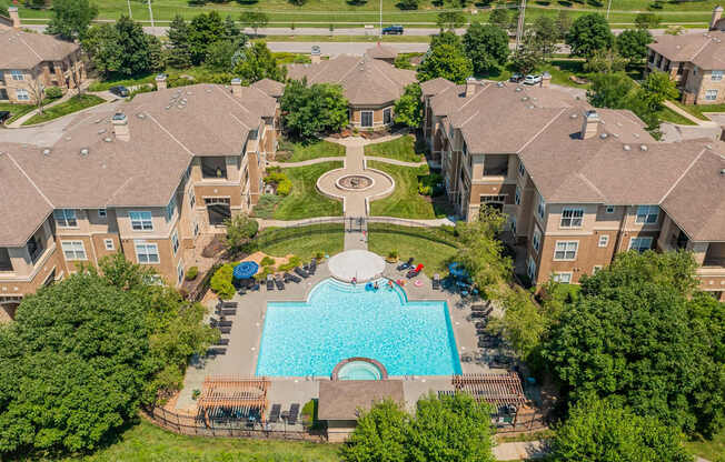 An aerial view of a swimming pool and courtyard surrounded by apartment buildings.