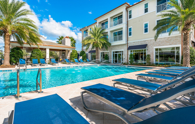 View of Pool Area, Showing Loungers, Palm Trees, Grilling Lounge, and Building at The Marq Highland Park Apartments