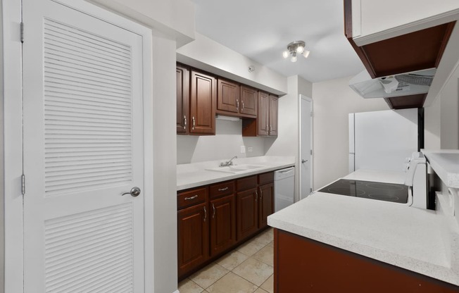 a kitchen with white counter tops and wooden cabinets and a white refrigerator