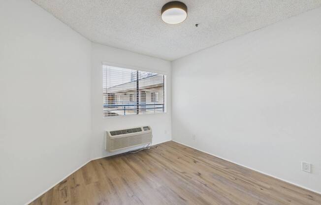 A room with a window and a wall-mounted air conditioner.