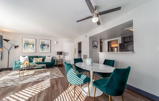 a living room with a table and chairs and a ceiling fan