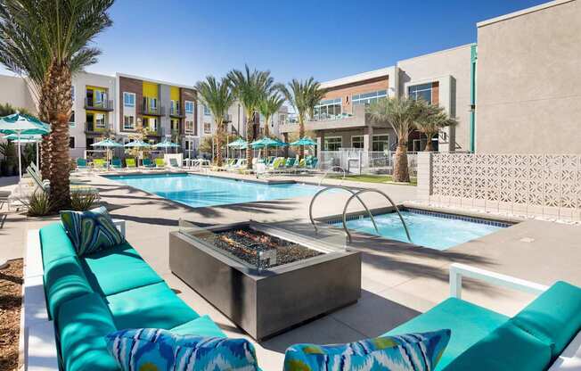 A pool area with a fire pit and lounge chairs.