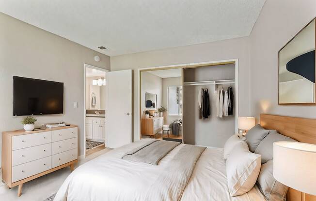 A bedroom with a large bed and a dresser with a flat screen TV on top.