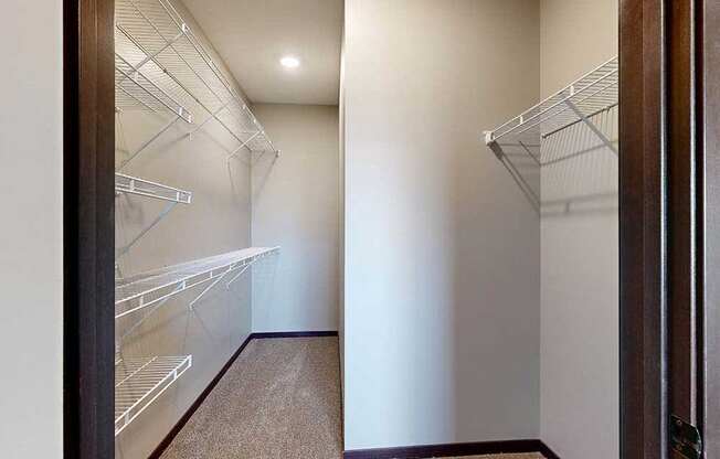 A long walk-in closet with built-in shelves along the left, and additional hanging space on the right.