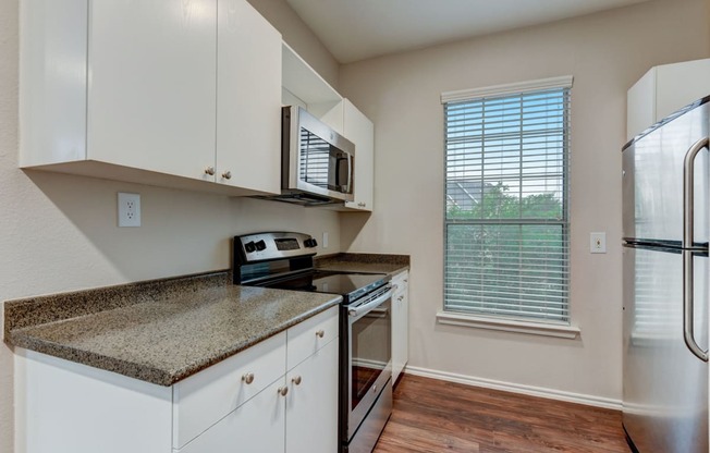 a kitchen with white cabinets and granite counter tops and a stainless steel refrigerator