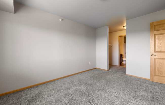 a bedroom with grey carpet and a wooden door