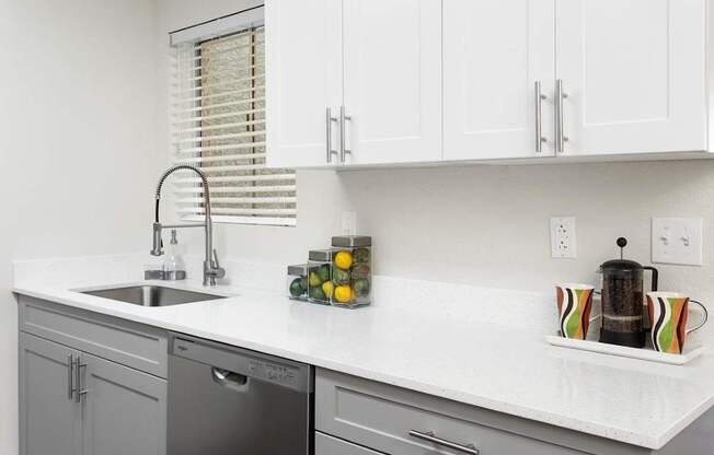 A kitchen with a white countertop and grey cabinets.