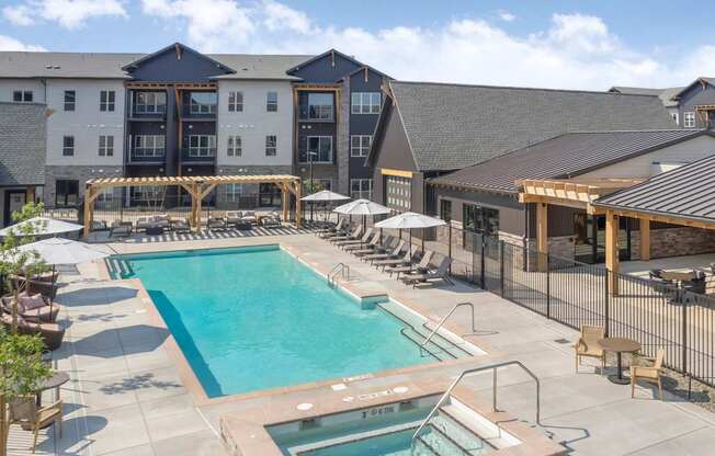 A large outdoor swimming pool surrounded by lounge chairs and umbrellas.