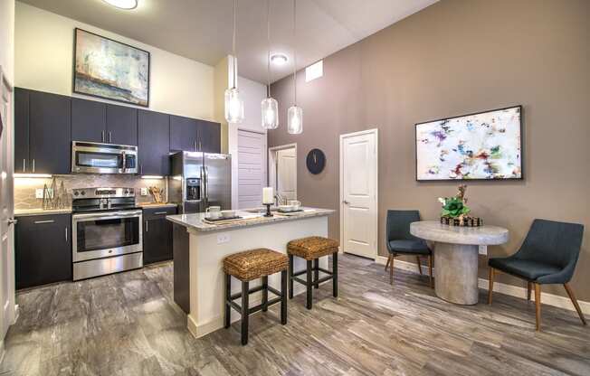 a kitchen with stainless steel appliances and a bar with stools at South Side Flats, Dallas
