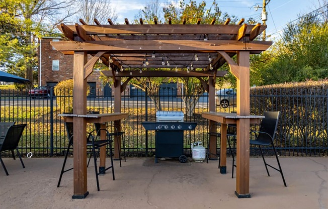 a pergola with two tables and a grill