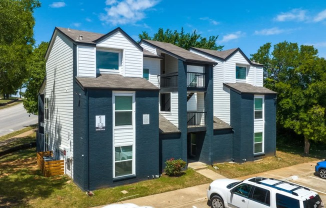 A white car is parked in front of a blue building.