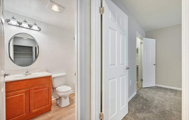 view into a bathroom with a mirror, a toilet and a sink from a hallway at ReNew Odenton