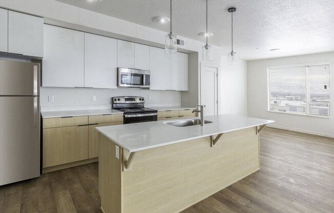 A kitchen with a refrigerator, microwave, oven, and sink.