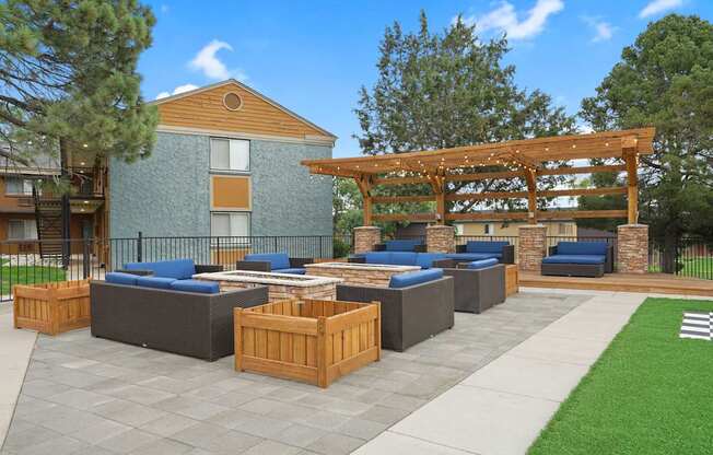 A patio with a wooden pergola and grey cushioned seating at Mountain Vista Apartments, Colorado
