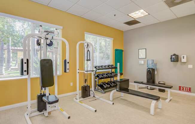 a fitness room with exercise equipment at the whispering winds apartments in pearland, tx