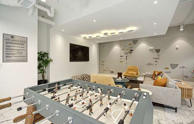 a game room with a foosball table and a couch at Link Apartments® Calyx, Chapel Hill, NC