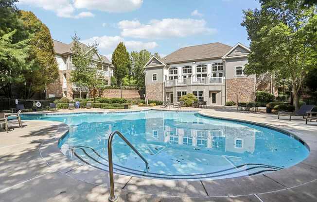 A swimming pool in front of a house with a brick wall.