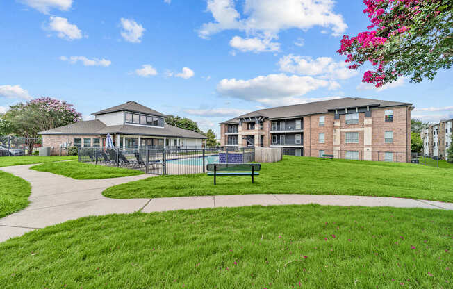 A grassy area with a building and a fence in the background.